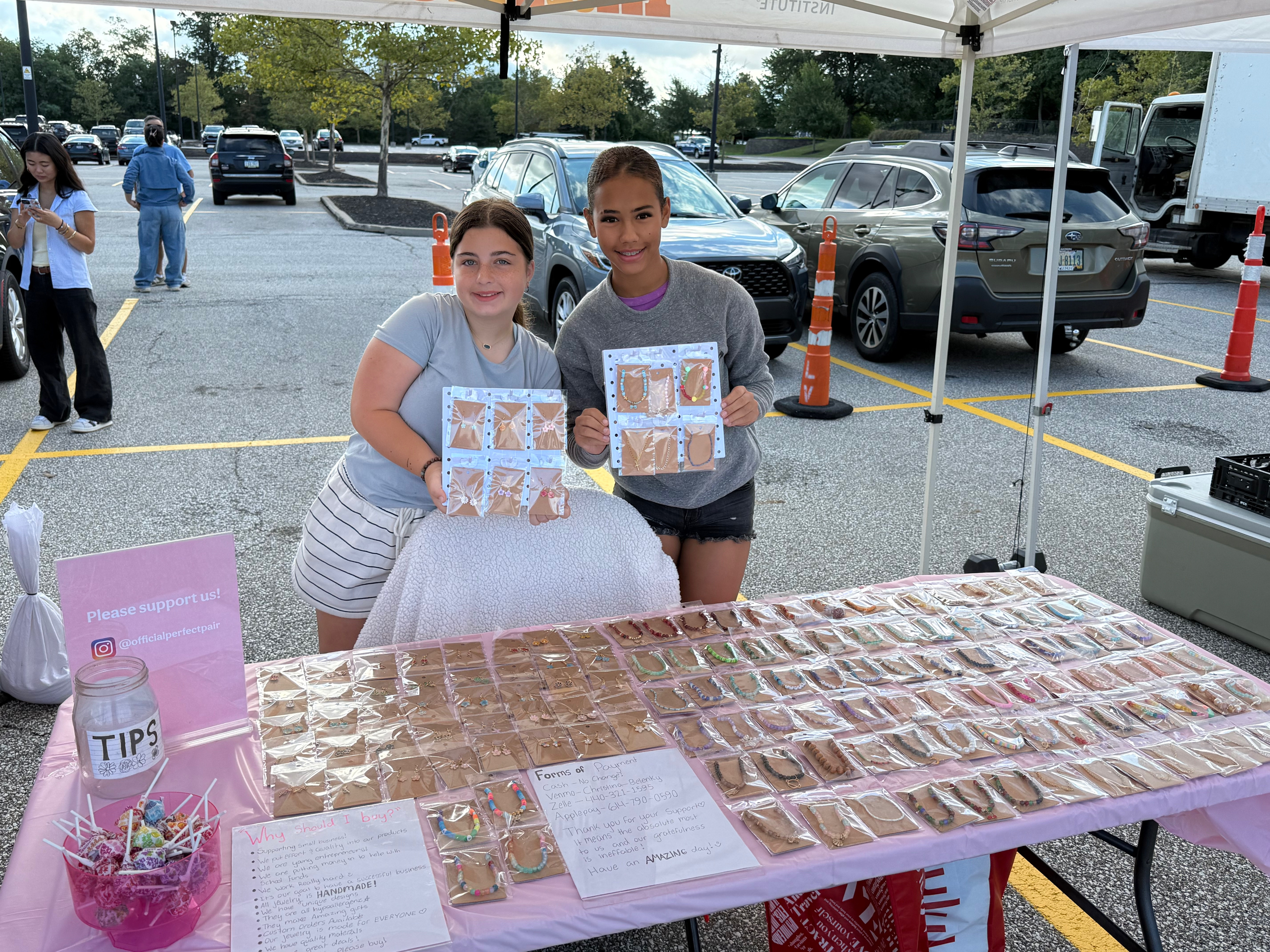 Perfect Pair founders at their pink farmers market table full of handmade bracelets